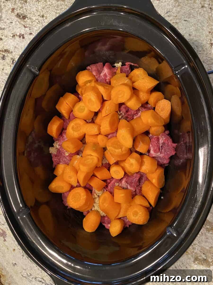 Classic Irish Beef Stew Recipe for Tender, Rich Flavor 11 Carrots on top of beef in a crockpot.