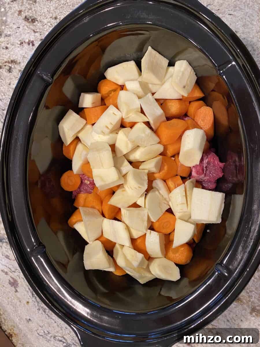 Classic Irish Beef Stew Recipe for Tender, Rich Flavor 12 Carrots and parsnips on top beef in a crockpot.
