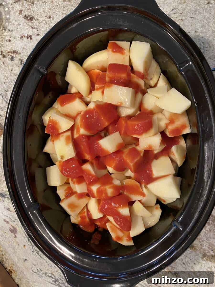 Classic Irish Beef Stew Recipe for Tender, Rich Flavor 14 Tomato sauce on top of veggies and beef in a crockpot.