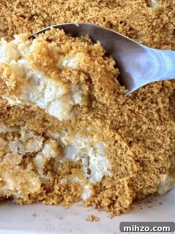 A spoon scooping up country potatoes from a baking dish.