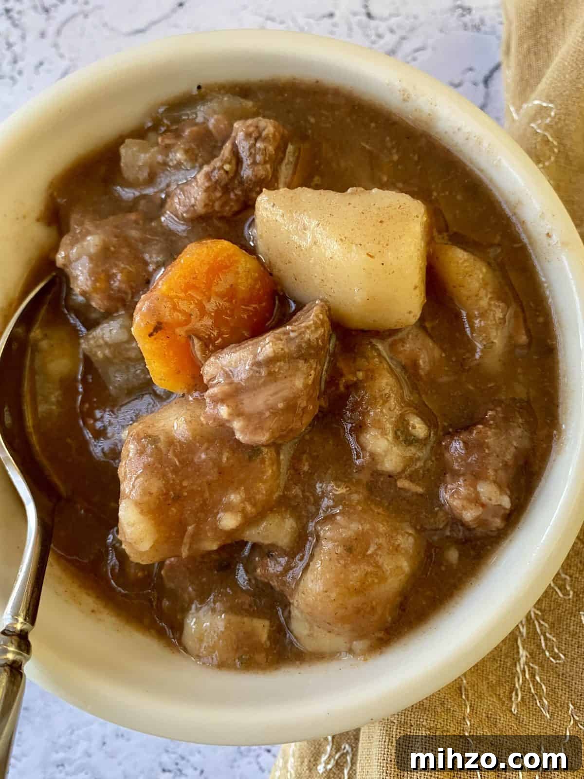 Classic Irish Beef Stew Recipe for Tender, Rich Flavor 4 A small bowl full of St. Patrick's Day Stew with a spoon and napkin on the side.