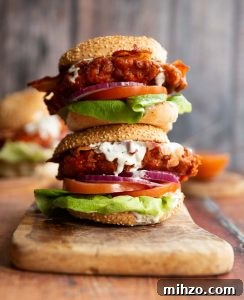 two chicken sandwich stacked on each other on wooden chopping board with blue cheese sauce dripping out