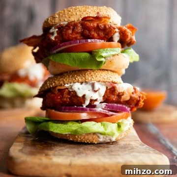 two chicken sandwich stacked on each other on wooden chopping board with blue cheese sauce dripping out