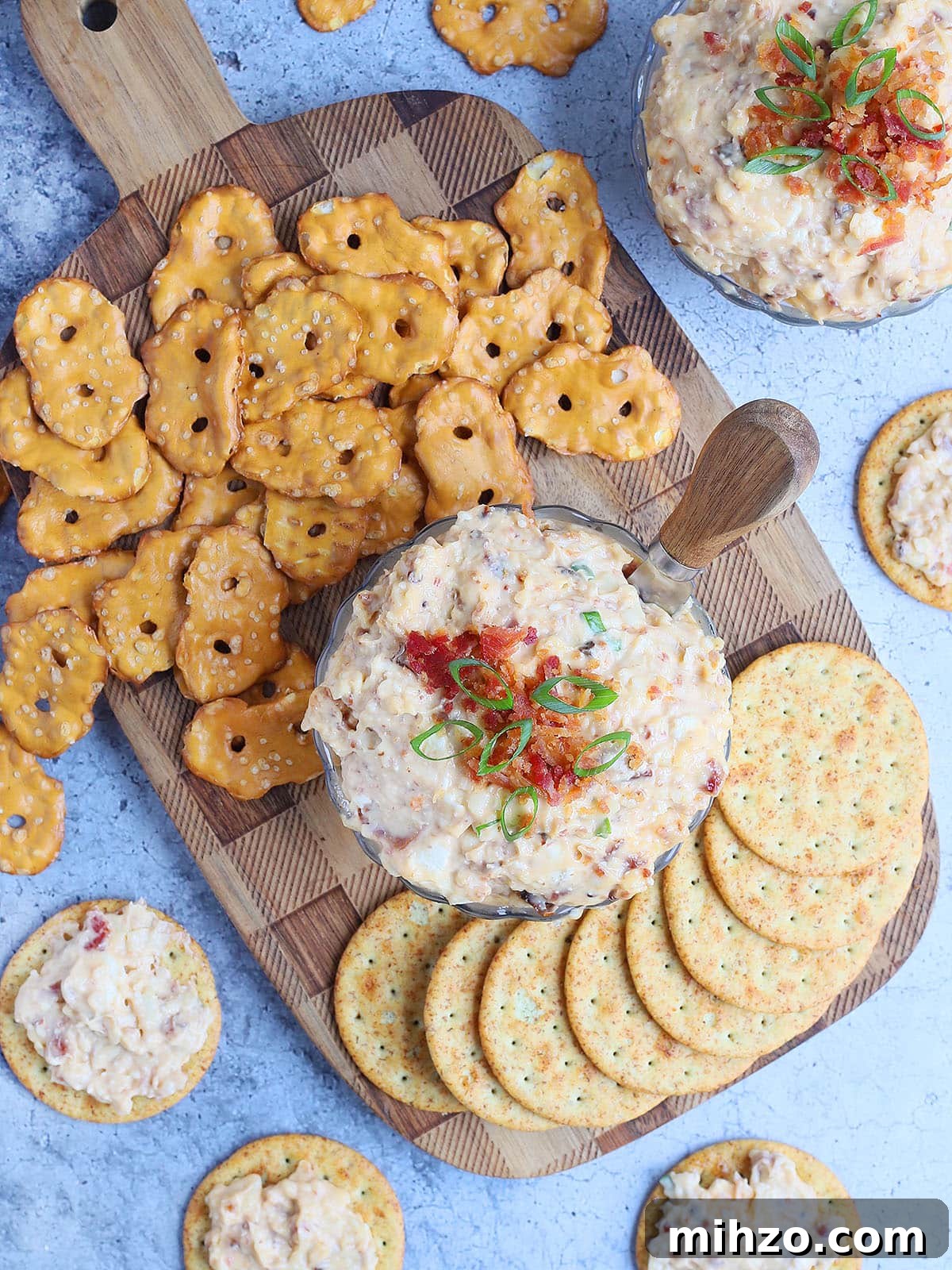 Smoky Chipotle Pimento Cheese Spread with a Spicy Kick 2 Dish of spicy pimento cheese topped with chopped bacon and green onions surrounded by pretzels and crackers.