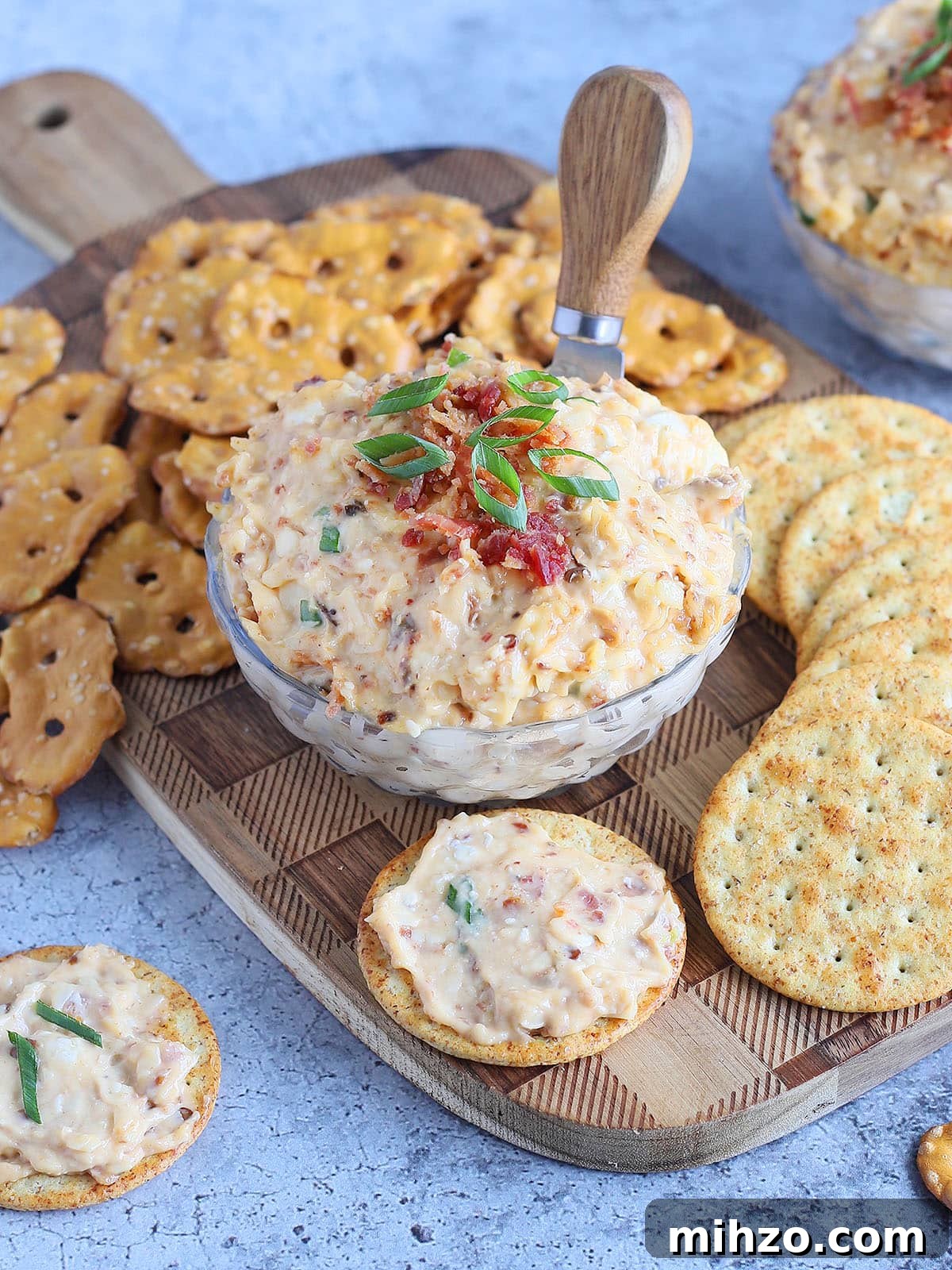 Smoky Chipotle Pimento Cheese Spread with a Spicy Kick 7 Dish of spicy pimento cheese topped with chopped bacon and green onions surrounded by pretzels and crackers.