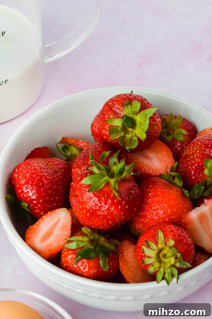 Chocolate-Strawberry Overnight Oats Recipe for Creamy Mornings 4 white bowl of fresh strawberries beside additional strawberry cinnamon roll ingredients.