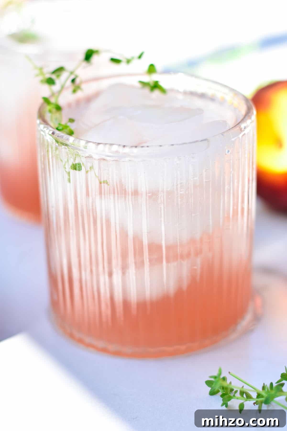 Refreshing Peach Mocktail Recipe for Summer Parties 2 Peach mocktail on a white table with the sun shining on it.