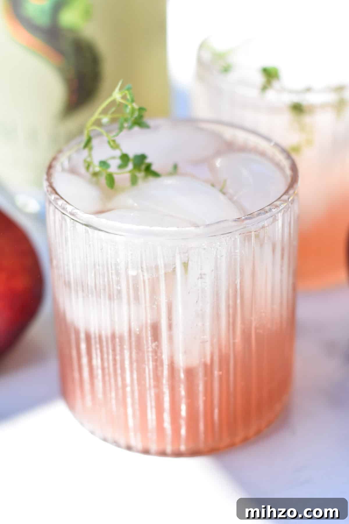 Refreshing Peach Mocktail Recipe for Summer Parties 5 A peach mocktail with ice next to a bottle of seedlip and peaches.