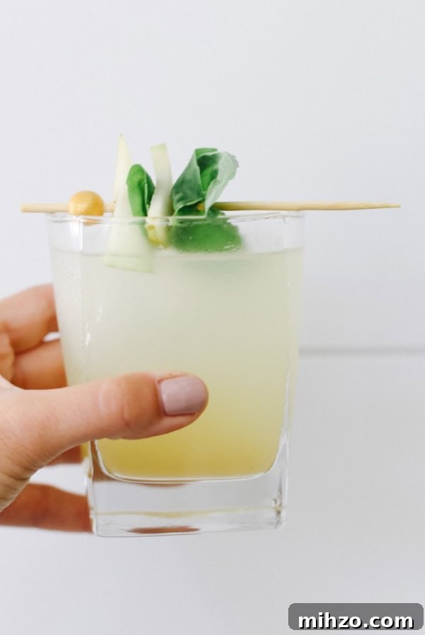 Refreshing Peach Mocktail Recipe for Summer Parties 7 A hand holding a pear mojito mocktail up against a white wall.