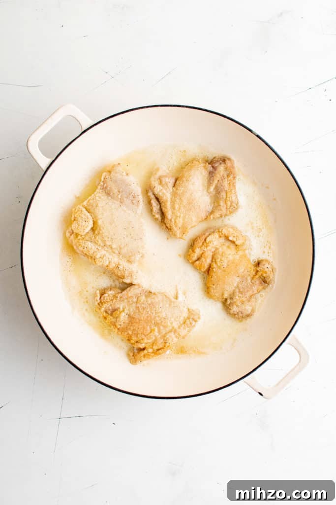 Chicken thighs cooking in a pan.