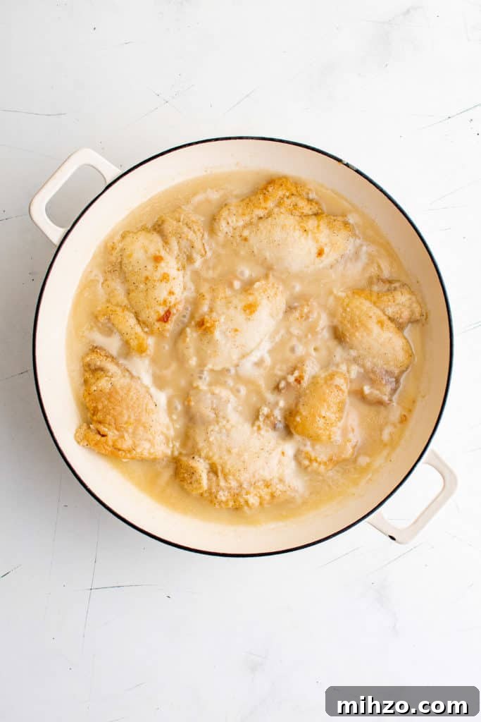 Chicken with lime coconut sauce cooking in a pan.