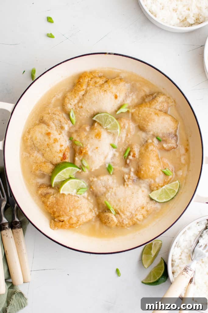 Pan of coconut chicken with lime wedges.