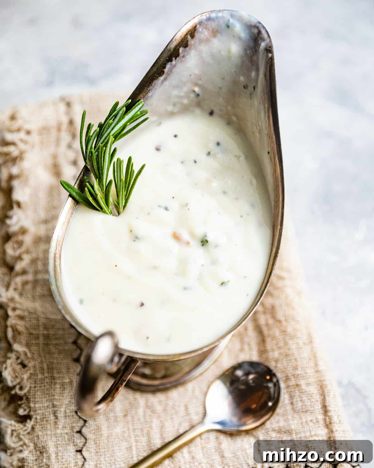 Creamy White Pepper Gravy Recipe for Biscuits and Roast 5 white pepper gravy in a gravy boat next to a serving spoon.