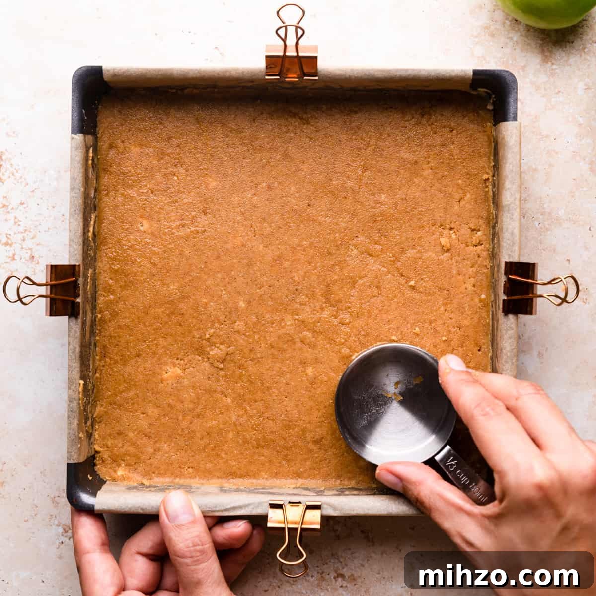 cheesecake crust being pressed into baking tin.