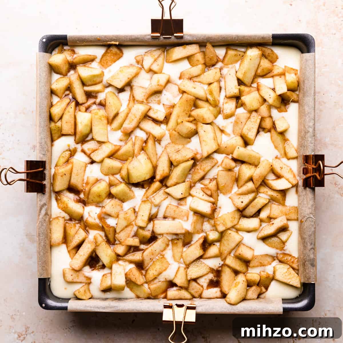 baking pan with cheesecake batter topped with spiced apples.