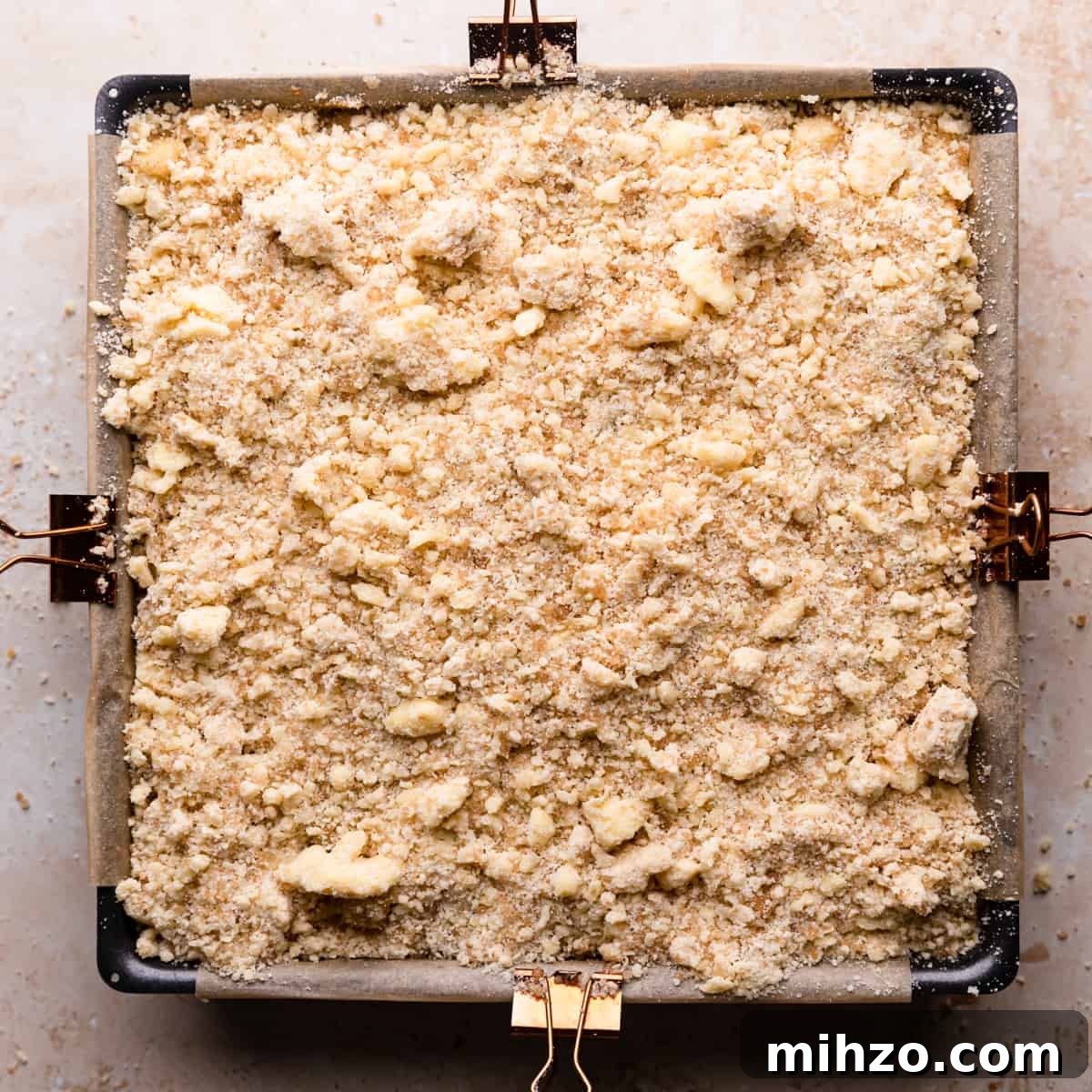 square baking pan with apple cheesecake topped with crumble.