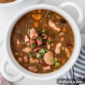 A bowl of soup filled with juicy beans and ham chunks.