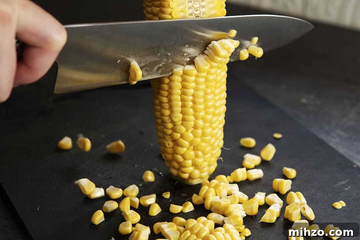 Authentic Cajun Maque Choux Recipe with Sweet Corn and Bacon 4 Cutting corn off the cob
