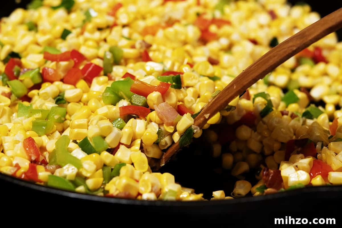 Authentic Cajun Maque Choux Recipe with Sweet Corn and Bacon 7 stirring corn kernels into bell pepper mixture