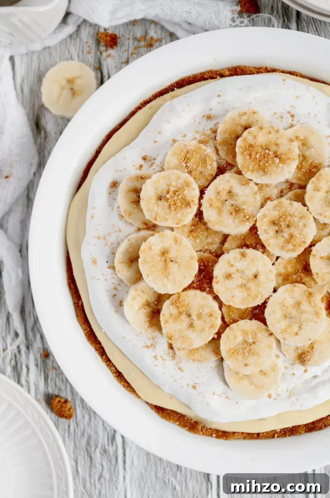 A vegan banana cream pie topped with bright white fluffy whipped topping and banana slices.
