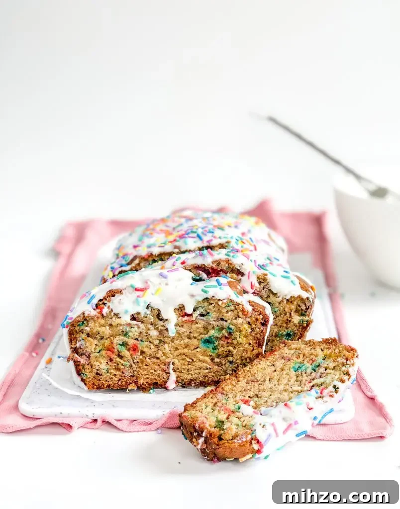 Sliced funfetti banana bread on a white cutting board.