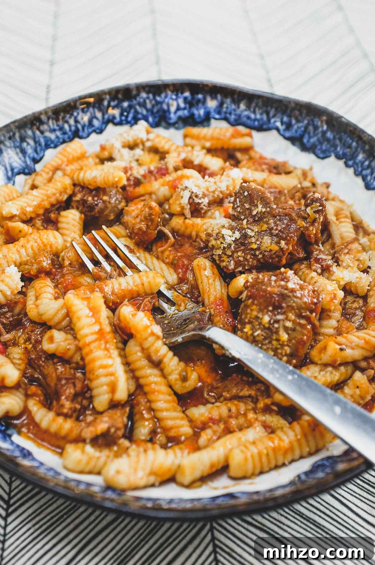 Cavatelli with Pork Ragù | cookeatworld.com A bowl of cavatelli pasta with pork ragù with a fork
