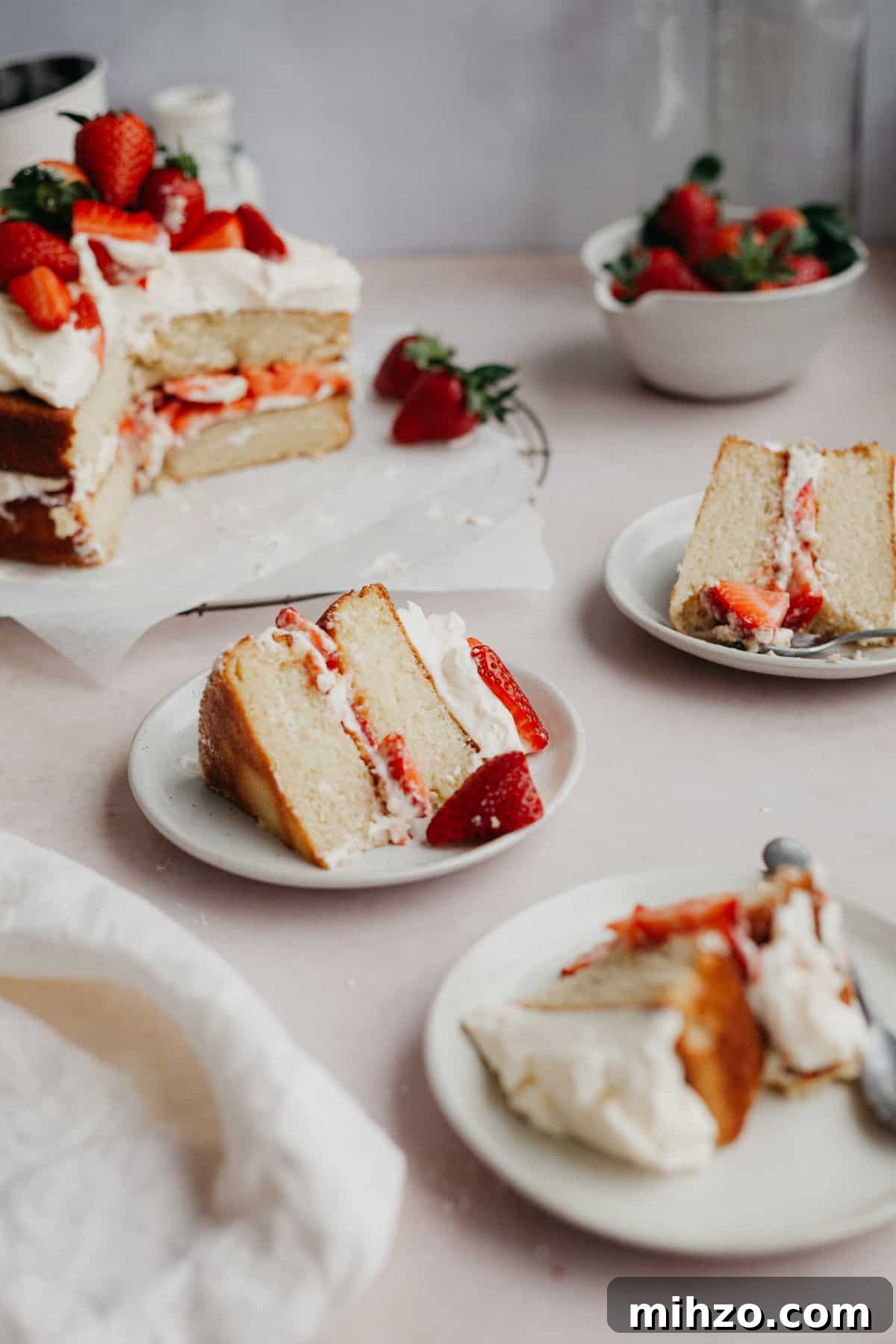 Three slices of white cake with strawberry filling on small beige plates.