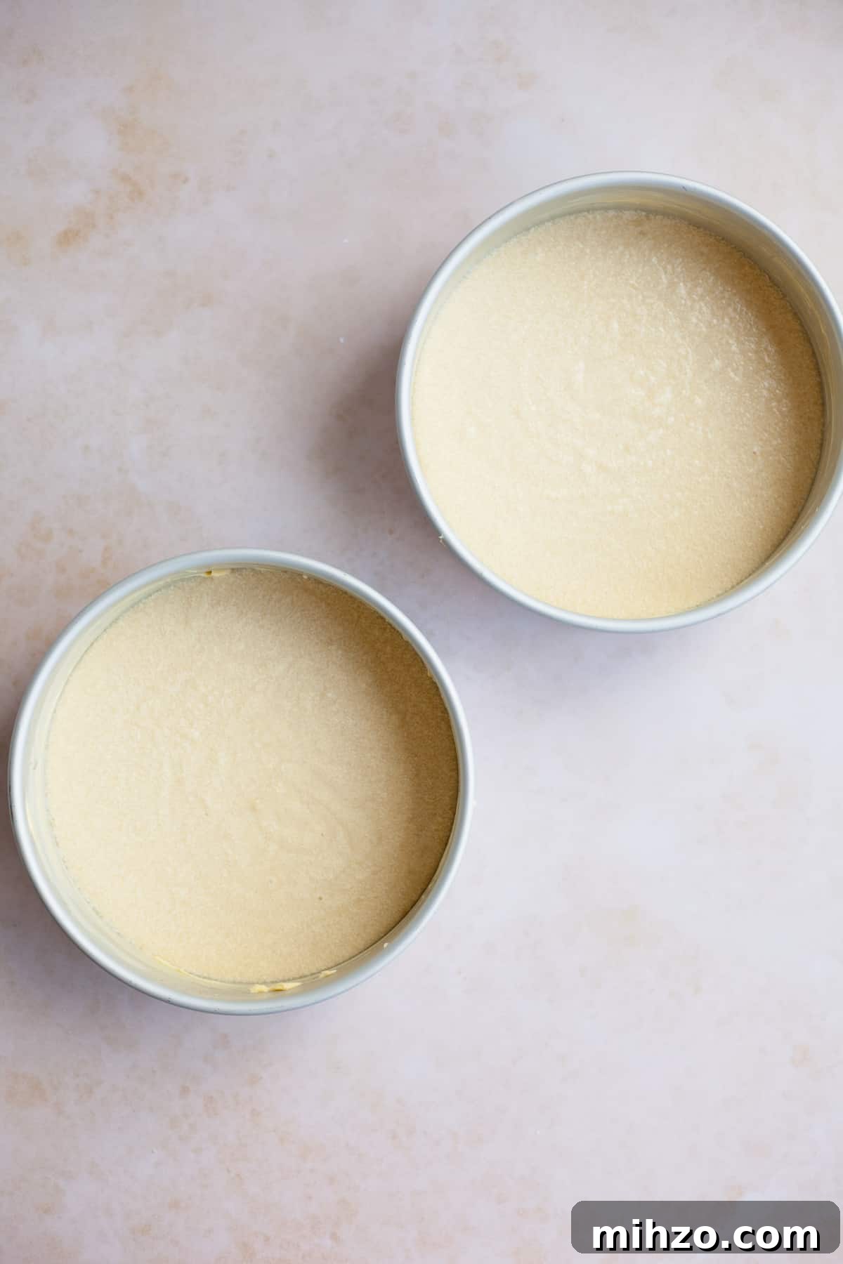 Two silver cake tins with unbaked cake batter