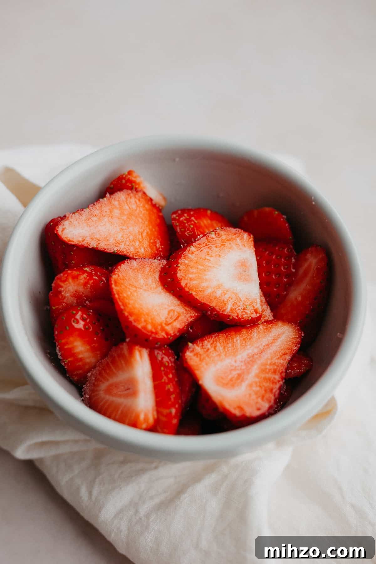 A small grey bowl filled with sliced strawberries