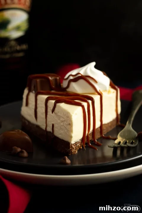 No-Bake Baileys Cheesecake Recipe: Creamy Irish Cream Dessert 10 A slice of no bake Baileys cheesecake on a dark grey plate with a fork and a Baileys chocolate