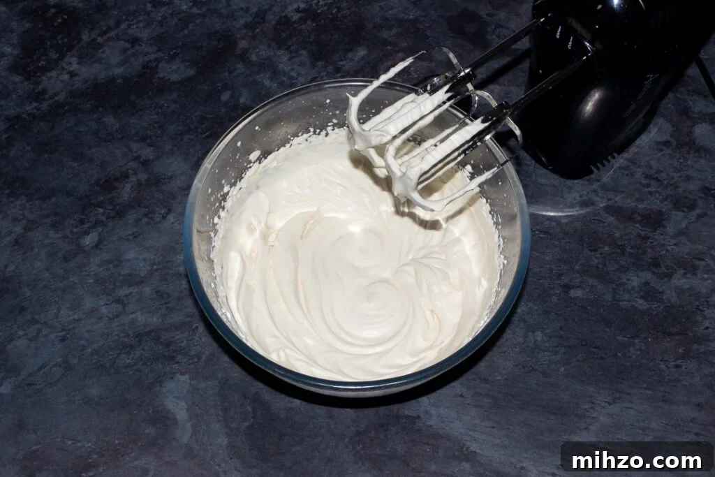 No-Bake Baileys Cheesecake Recipe: Creamy Irish Cream Dessert 13 Whipped Baileys and double cream in a glass bowl with an electric hand whisk