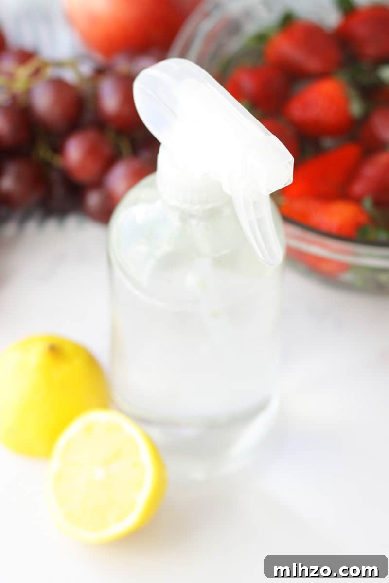 Wash Fruit with Vinegar: DIY Produce Cleaning Spray 2 a clear glass spray bottle with fruit laying around it