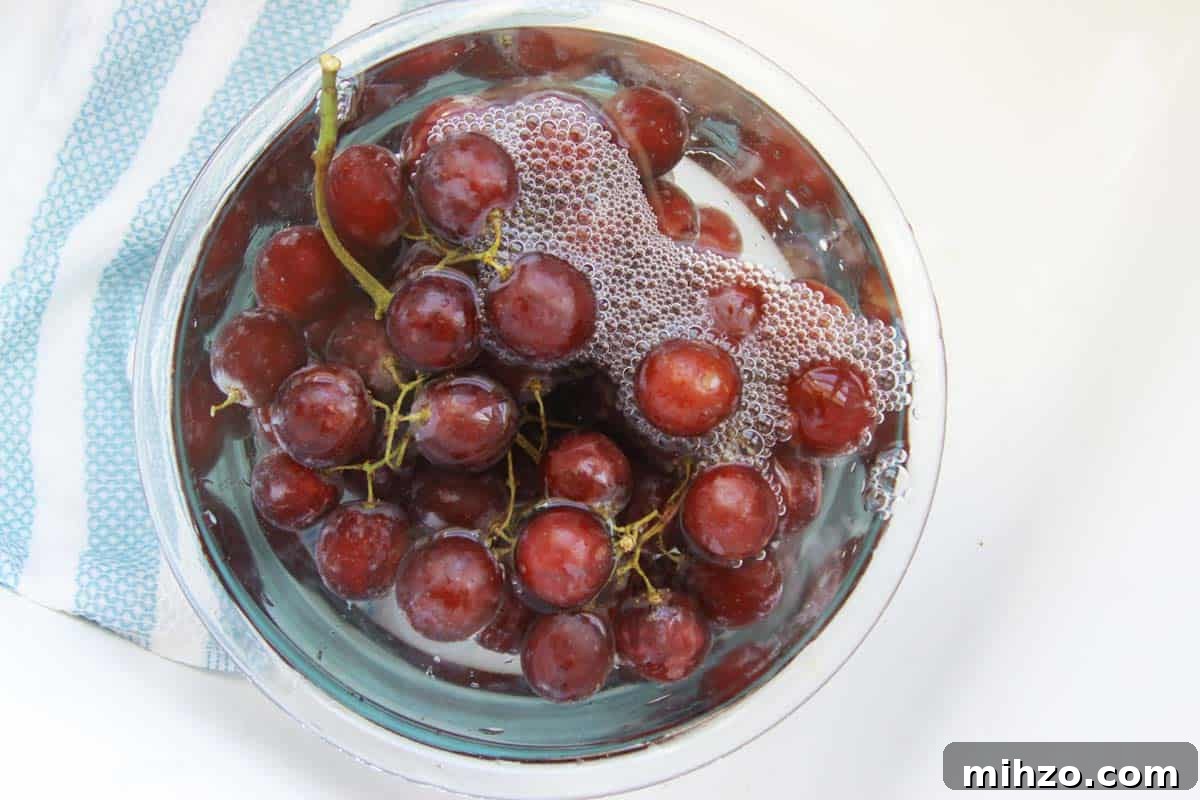 Wash Fruit with Vinegar: DIY Produce Cleaning Spray 3 grapes soaking in a bowl of water and vinegar
