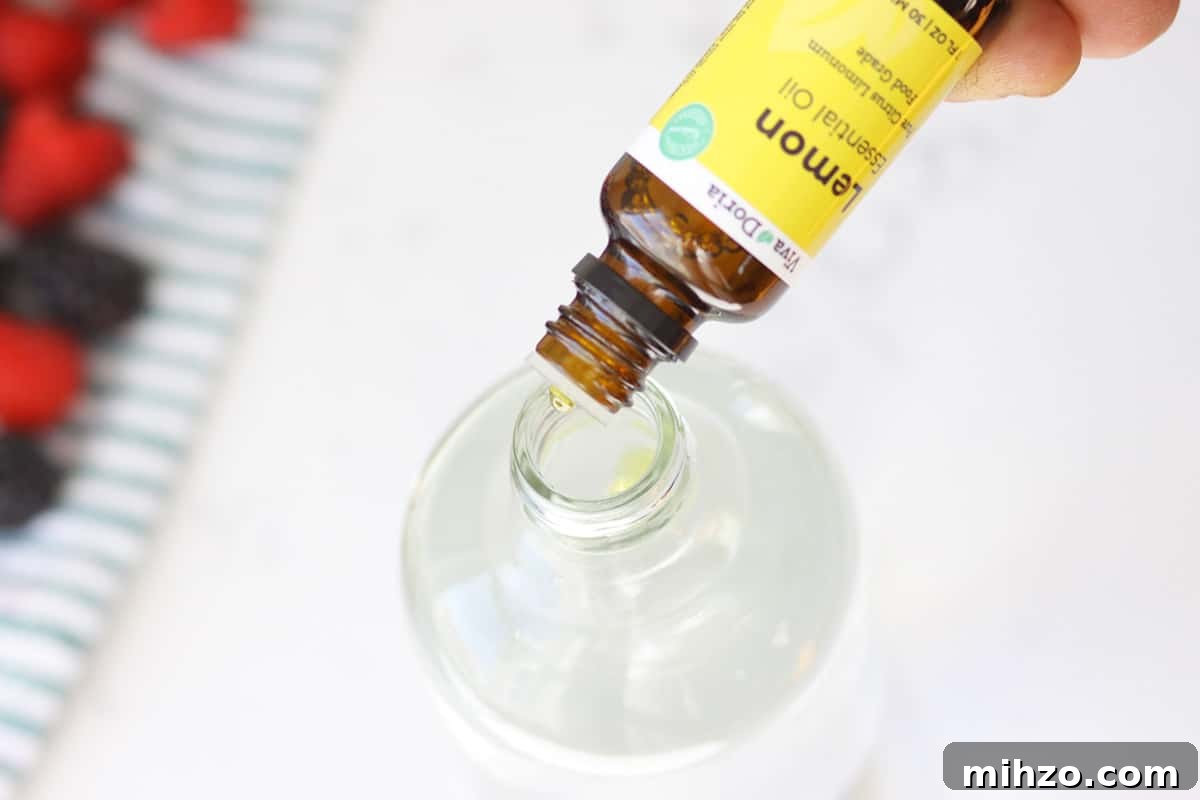 Wash Fruit with Vinegar: DIY Produce Cleaning Spray 7 lemon essential oil being poured into a glass spray bottle next to a towel with washed fruit on it