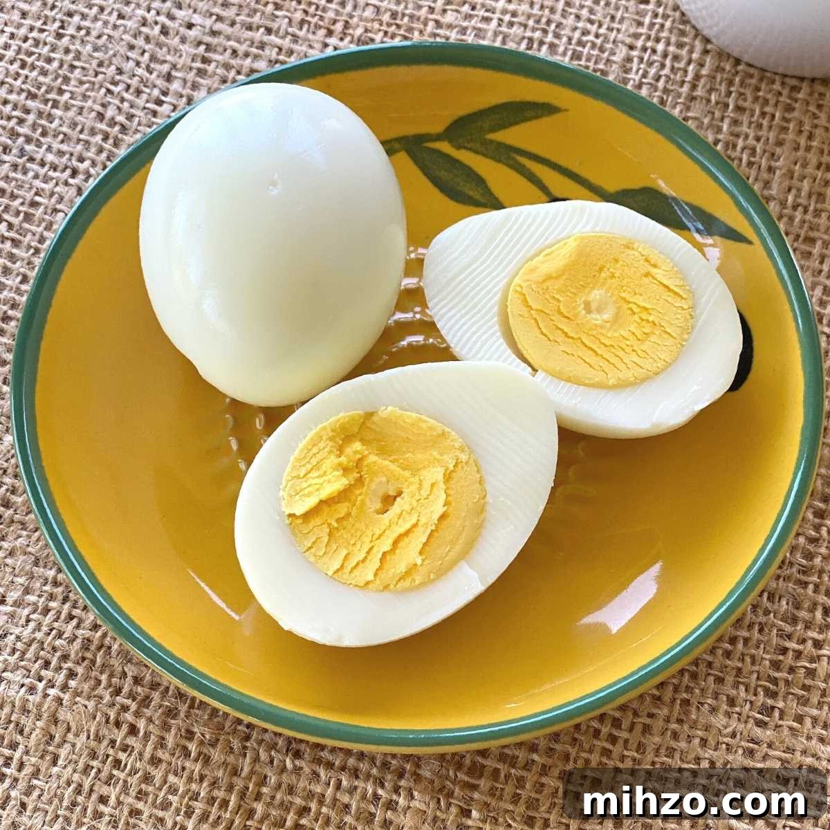 2 hard boiled eggs cooked in a Ninja Air Fryer. 1 is whole, the other cut in half.