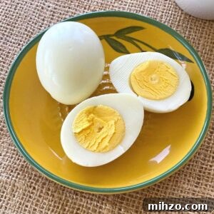 2 hard boiled eggs cooked in a Ninja Air Fryer. 1 is whole, the other cut in half.