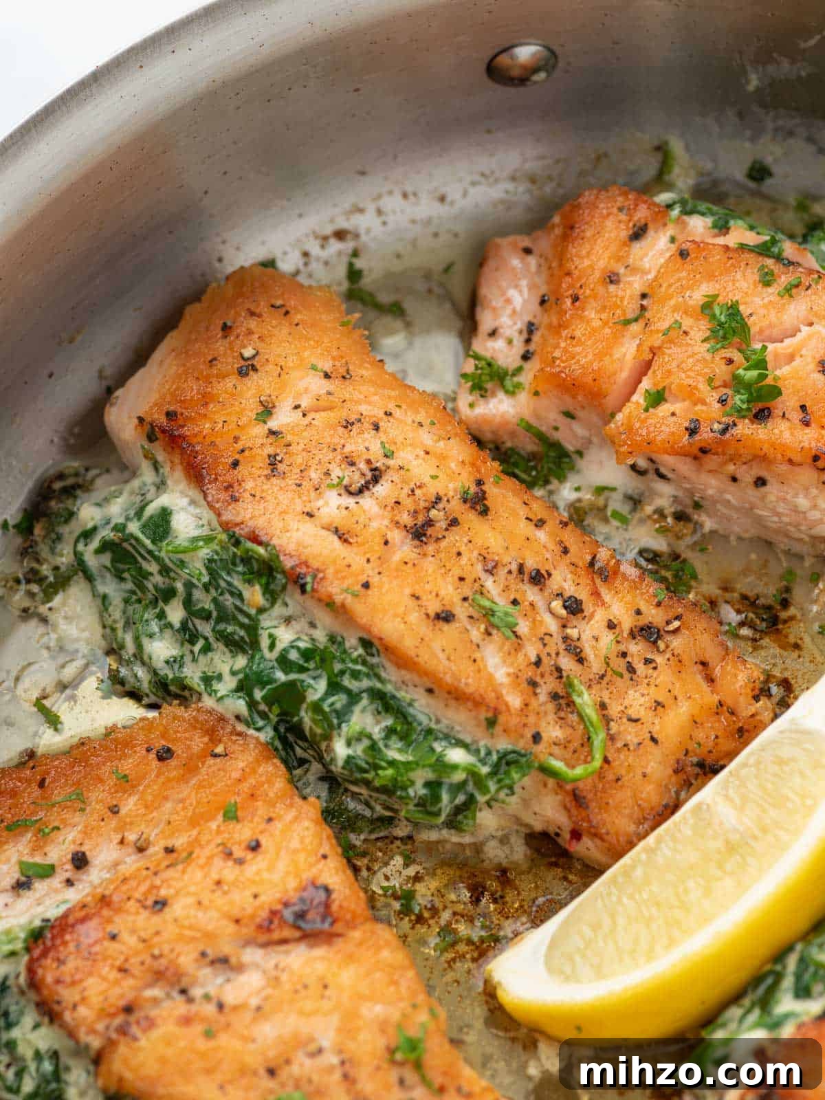Creamy Spinach-Stuffed Salmon Fillets with Garlic Butter 9 A pan of creamy stuffed spinach salmon with a lemon wedge.
