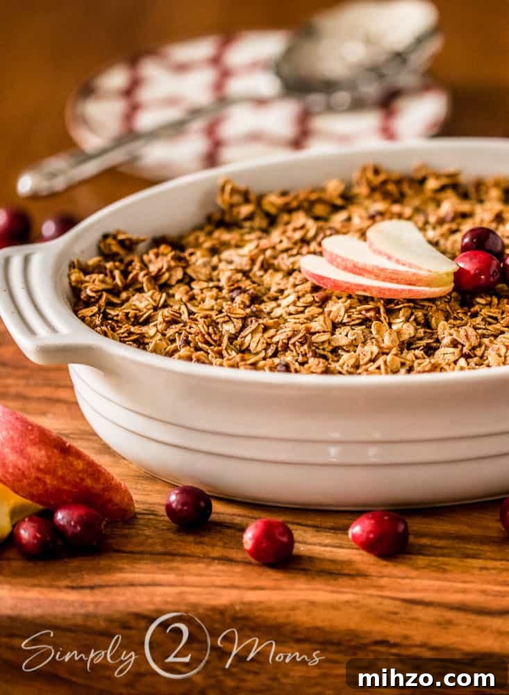 13+ Creative Ways to Make Your Thanksgiving Memorable 12 oval casserole dish with baked cranberry apple casserole on a wood board with an apple and sticks of cinnamon