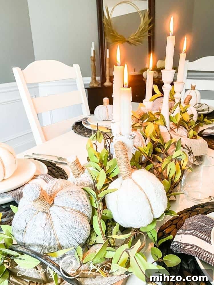 13+ Creative Ways to Make Your Thanksgiving Memorable 3 diy sweater pumpkins on garland of leaves and twigs in middle of dining room table with candles