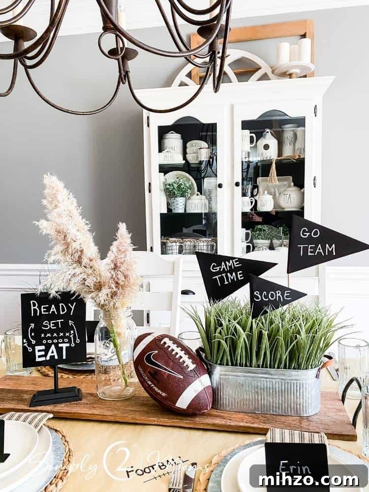 13+ Creative Ways to Make Your Thanksgiving Memorable 5 football themed centerpiece arrangement on long wood tray with faux grass plant in galvanized planter and diy chalkboard flags, football, mason jar with pampas grass and chalkboard sign