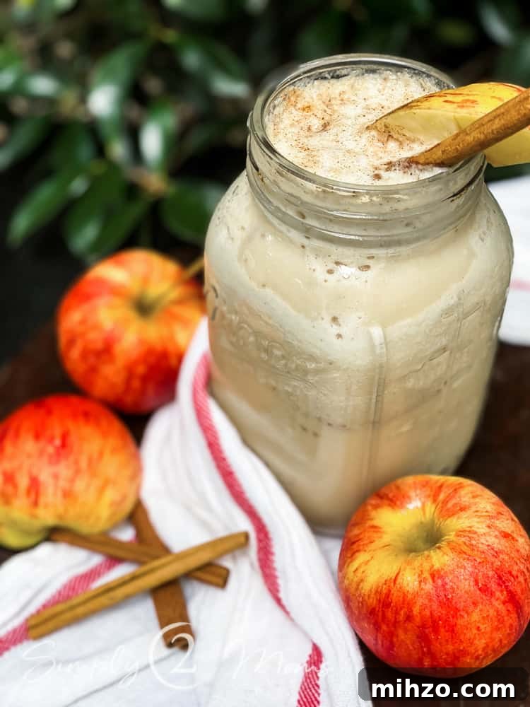13+ Creative Ways to Make Your Thanksgiving Memorable 10 A large mason jar with an apple pie protein shake garnished with a slice of apple and a stick of cinnamon sitting on a striped piece of fabric surrounded by several apples and a stack of cinnamon sticks on a wood table with leaves in the background