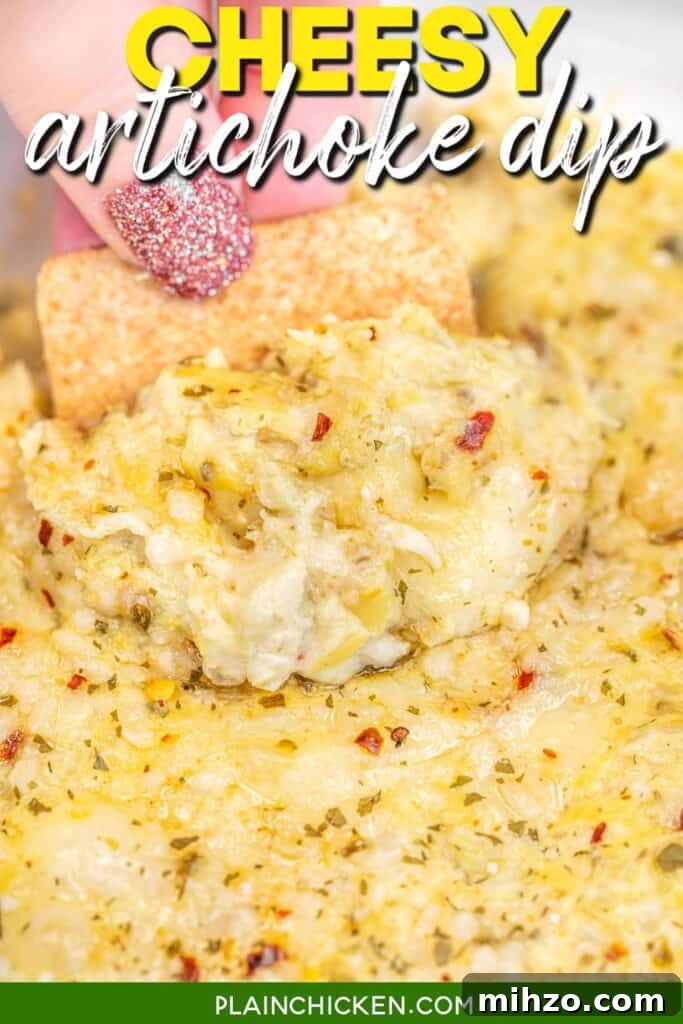 scooping cheesy artichoke dip from a baking dish with a wheat thin cracker with text overlay
