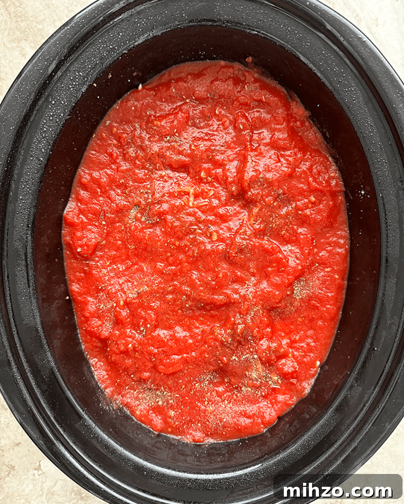 overhead shot of uncooked ravioli casserole in a black slow cooker