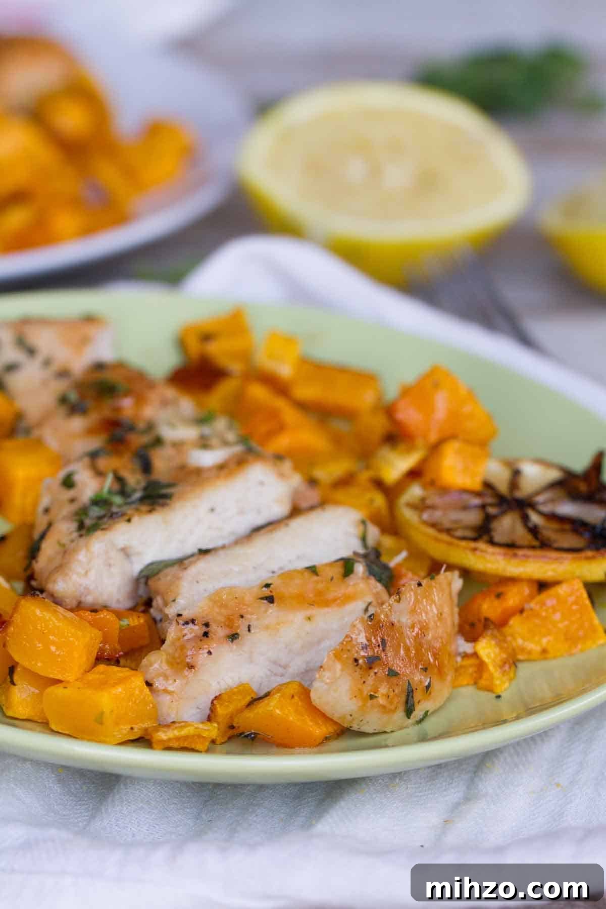 chicken breast sliced with butternut squash and lemons on the plate