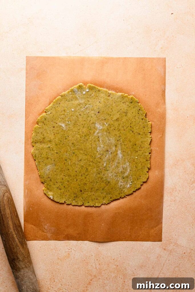 Pistachio Frangipane Tart Recipe — Crunchy Almond-Pistachio Filling 3 Dough rolled on top of a parchment paper with a rolling pin.