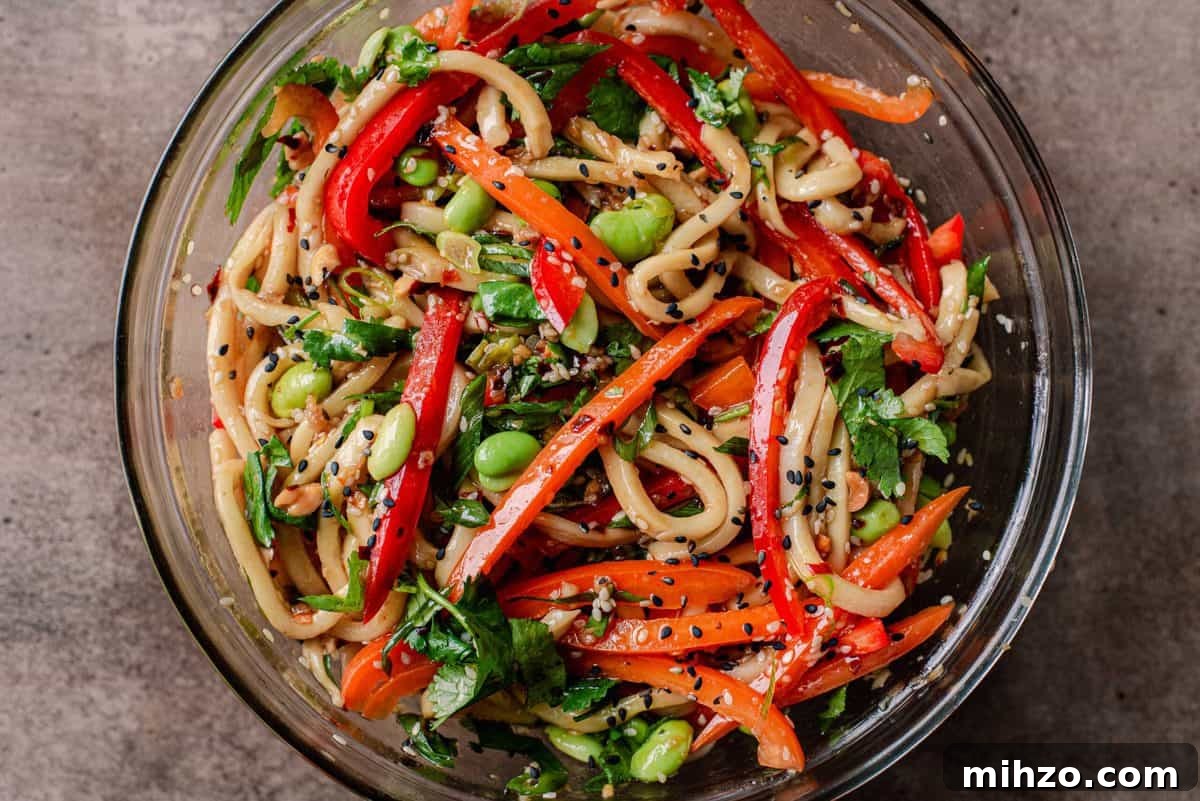 vegan noodles with bell peppers and edamame in glass bowl
