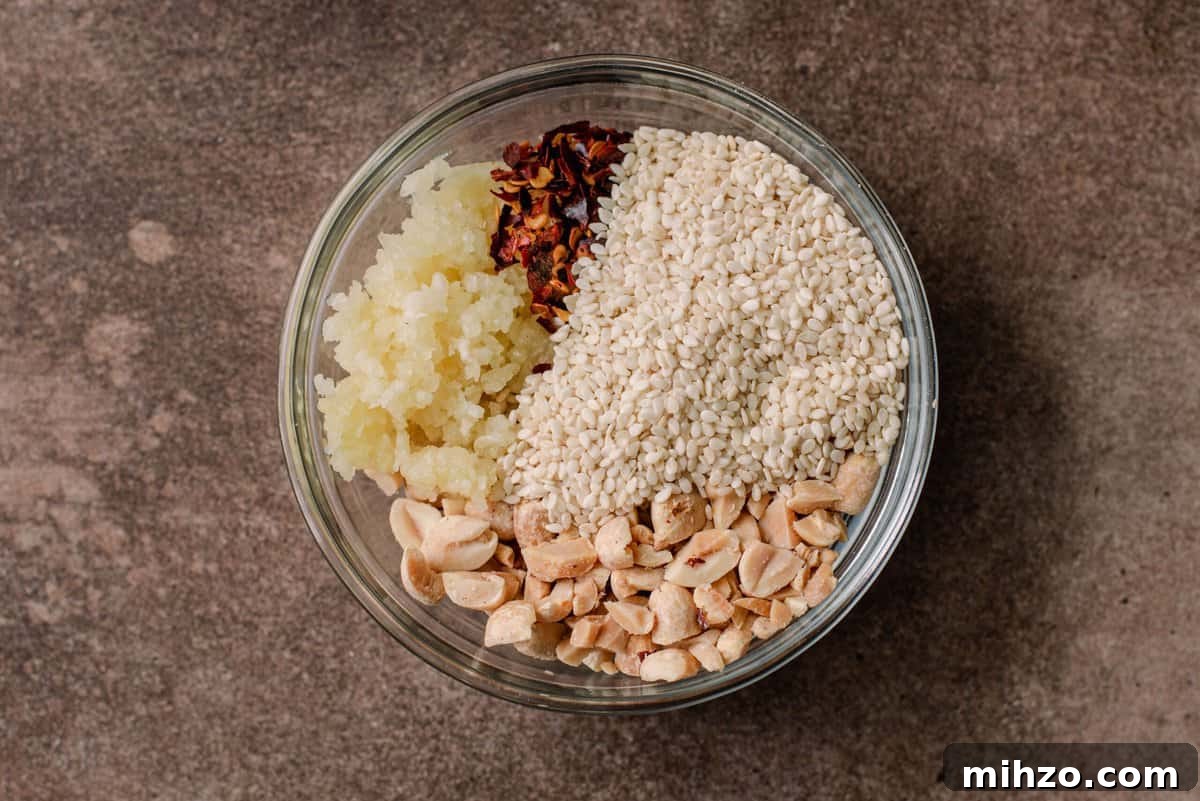 glass bowl with chopped peanuts, minced garlic, chile flakes, and sesame seeds 