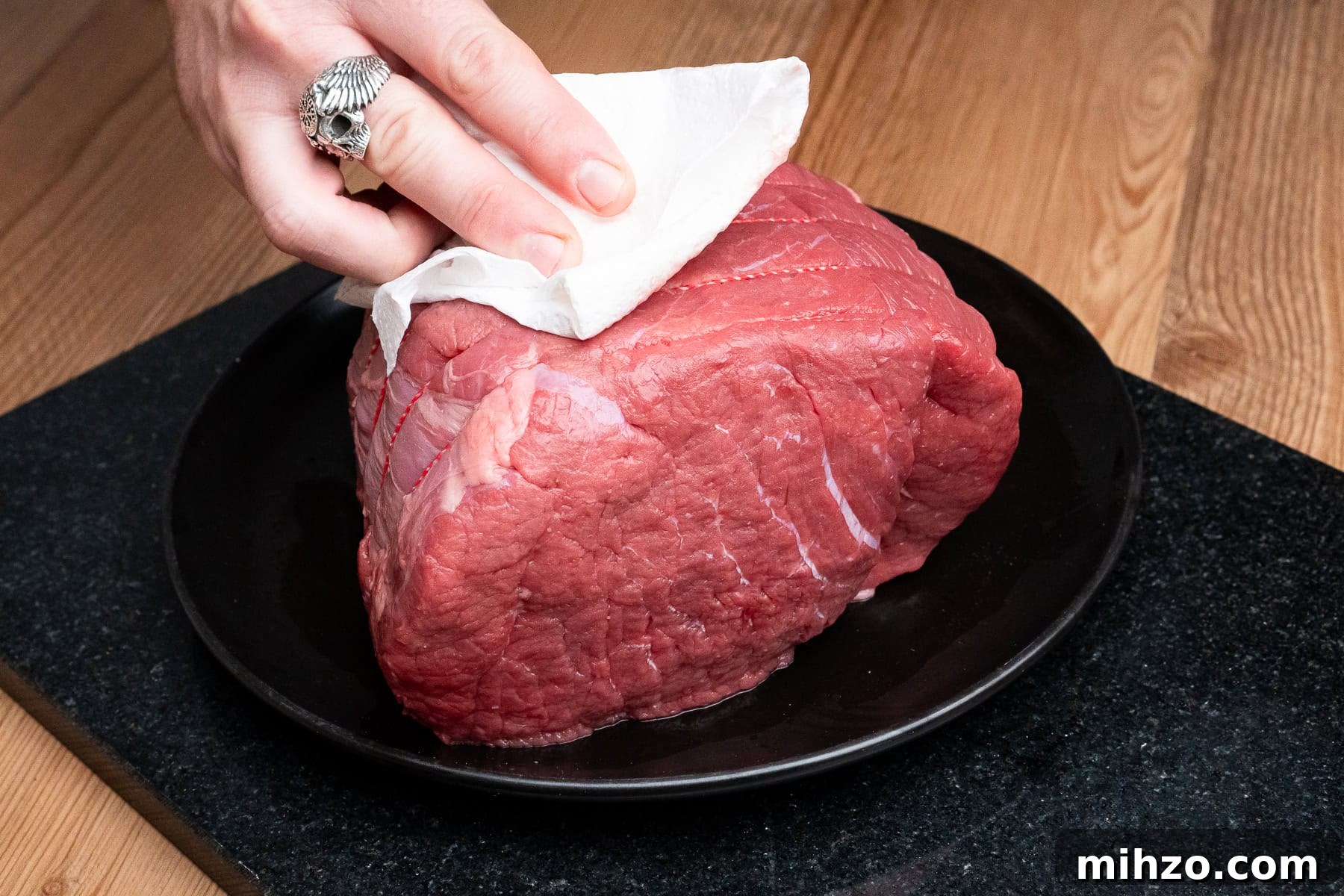 Patting beef joint with kitchen paper towel before cooking.