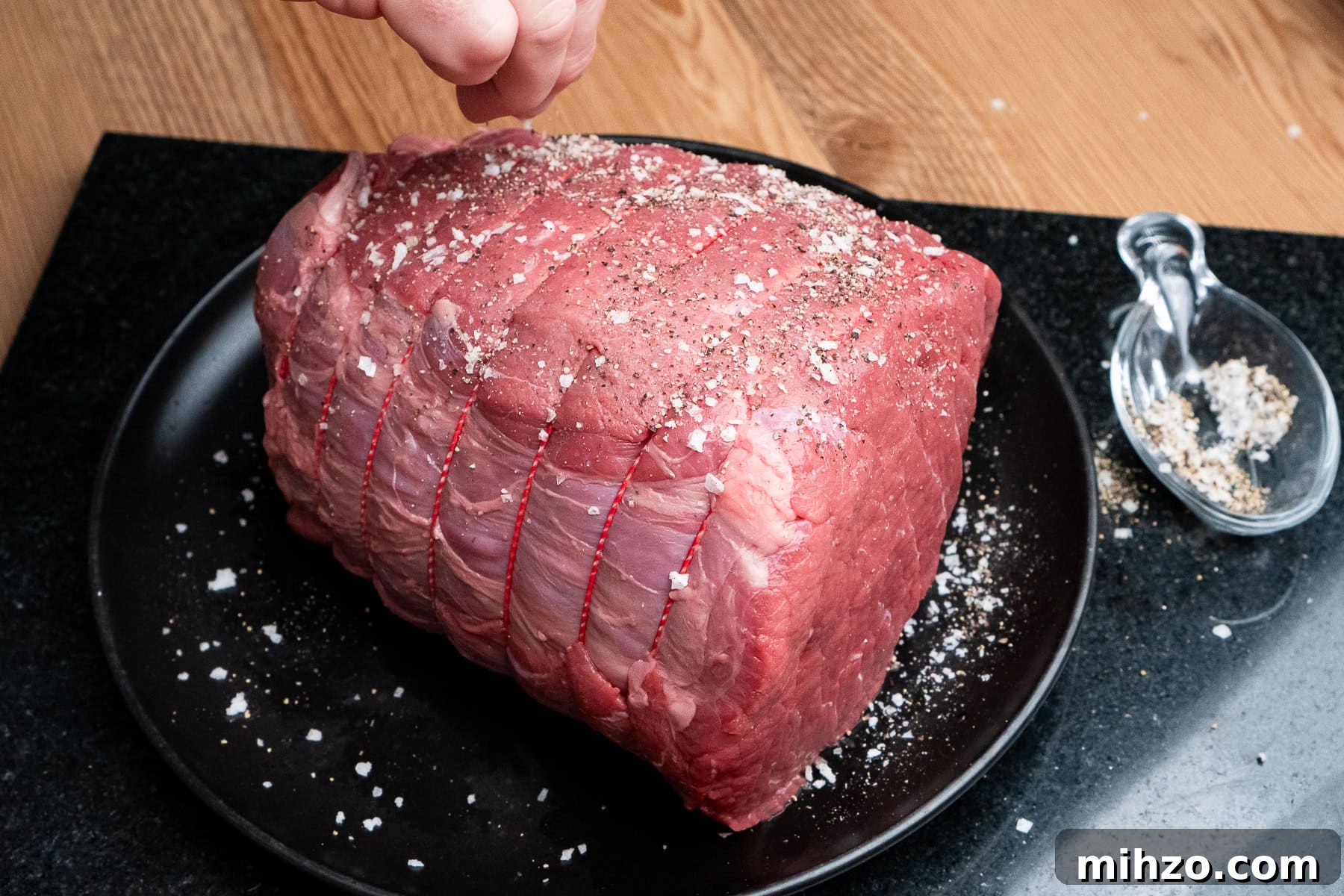 Seasoning a uncooked roast beef joint with salt and pepper