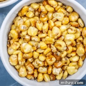 Crispy Homemade Corn Nuts: Fried or Baked Recipes 9 Close-up of a bowl filled with homemade corn nuts, featuring golden yellow and lightly browned baked corn kernels.